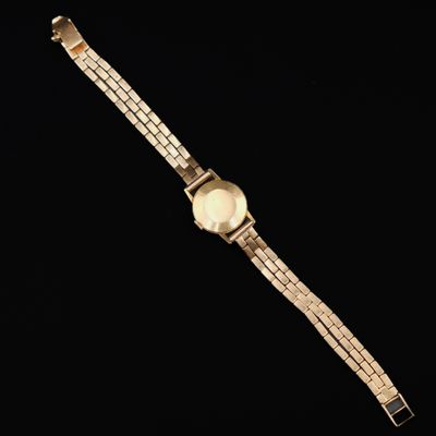 a close up of a watch on a black surface with a black background