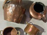 three cups and a pitcher sitting on a table next to each other