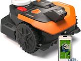 une tondeuse robotisée orange et noire à côté d'un téléphone portable
