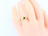 an image of a woman ' s hand with a gold ring with a green eye