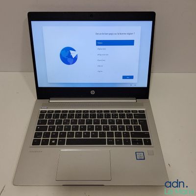 un ordinateur portable ouvert posé sur une table blanche