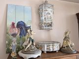 a painting on the wall above a dresser with statues on it