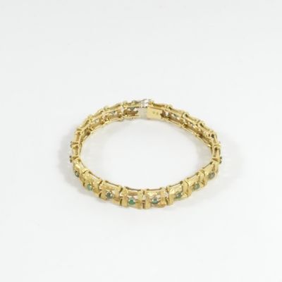 gros plan d'un bracelet en or sur fond blanc
