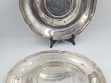 two silverplated dishes on stands on a white surface