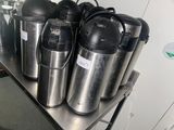many different types of coffee pots on a metal shelf
