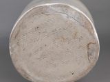 a close up of a silver vase on a gray surface