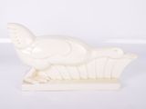 une image représentant une sculpture blanche d'un oiseau posé sur un socle en bois