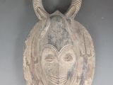 un masque accroché au mur, orné de cornes