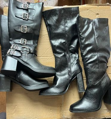 deux paires de bottes noires ornées de boucles, posées sur un carton