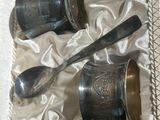 deux cuillères en argent et une tasse en argent dans une boîte
