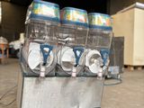 trois distributeurs de boissons gazeuses posés sur un chariot dans un entrepôt