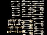 a group of silverware including forks and spoons on a black background
