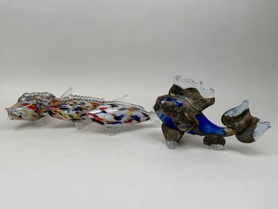 two glass fish sitting next to each other on a white surface