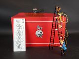 figurines représentant un pompier grimpant à une échelle à côté d'une boîte rouge