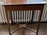 une petite table en bois avec un plateau en marbre, placée devant un radiateur