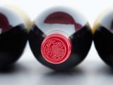 three bottles of red wine sitting next to each other on a white surface