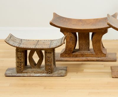 un banc en bois et deux petits tabourets posés sur un parquet