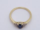 a close up of a gold ring with a sapphire and diamonds