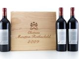 three bottles of red wine in front of a wooden box