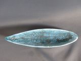 une assiette bleue avec un poisson dessus, posée sur une table