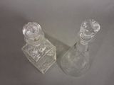 two clear glass perfume bottles sitting next to each other on a table