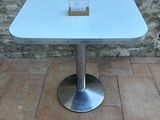 a white table with a glass top sitting on a brick floor