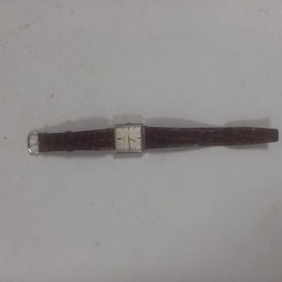 une image d'une montre sur une surface blanche avec un bracelet marron
