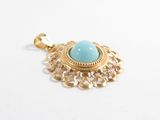 a close up of a gold pendant with a turquoise stone