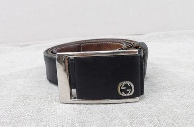 black leather belt with a silver buckle on a white surface