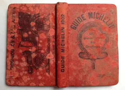 an old book with a red cover sitting on top of a table