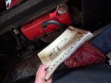 a man reading a newspaper underneath a car