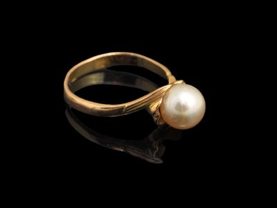 une bague en or sertie d'une perle sur fond noir