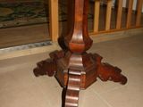 a wooden table with a carved top on a tile floor