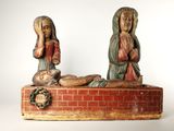 deux statues de Jésus et de Marie assis sur un mur de briques