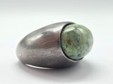 bague en argent avec une pierre verte au centre, sur un fond blanc