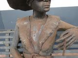 a statue of a man sitting on a bench with a hat on