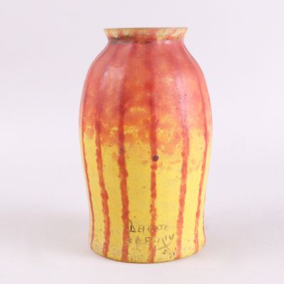 un vase jaune et rouge posé sur une surface blanche