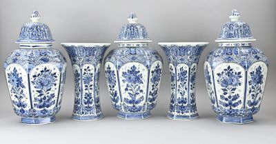 quatre vases bleus et blancs sont alignés sur un fond gris