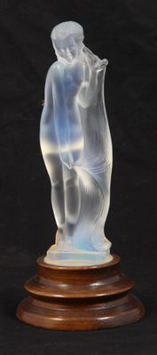 une photo d'une figurine en verre représentant une femme, posée sur un socle en bois