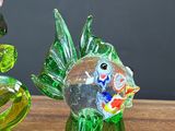 two glass fish figurines sitting on a wooden table