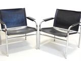 two black leather chairs sitting side by side on a white floor