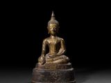une statue en bronze représentant un Bouddha assis sur un socle