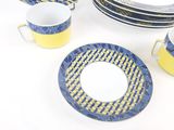 yellow and blue dishes and cups are arranged on a white table