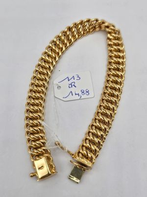 gros plan d'un bracelet en chaîne en or sur une surface blanche