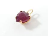 a close up of a red stone in a gold ring on a white surface