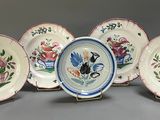 six plates with flowers and birds painted on them on a gray surface
