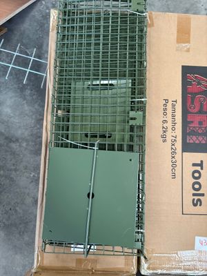 une boîte surmontée d'une cage, à côté d'une paire de ciseaux