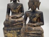 two statues of buddhas are sitting on blocks on a white surface