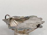 une assiette en argent ornée d'une fleur sur un fond blanc