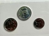 three different coins are shown in a clear box on a white surface